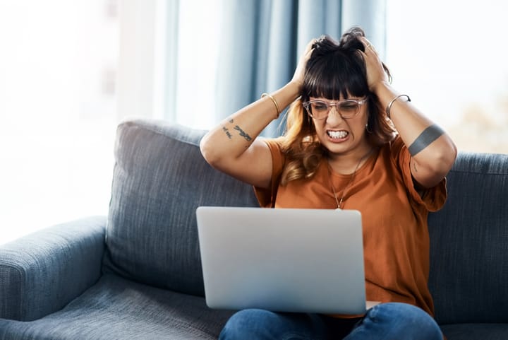 frustrated woman sitting on couch with a laptop